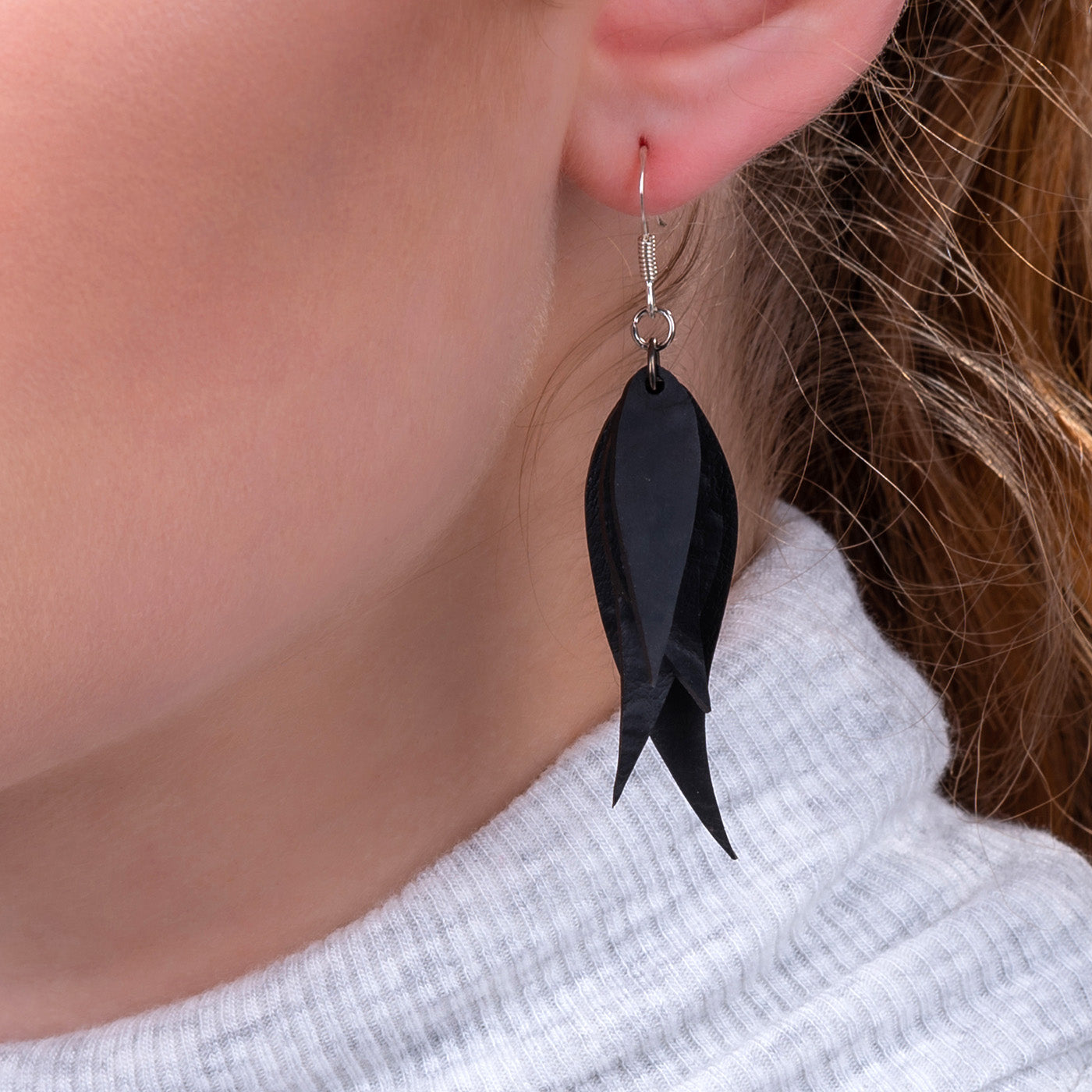 Paguro Upcycle recycled rubber earrings in black leaf design worn on ear with silver hook