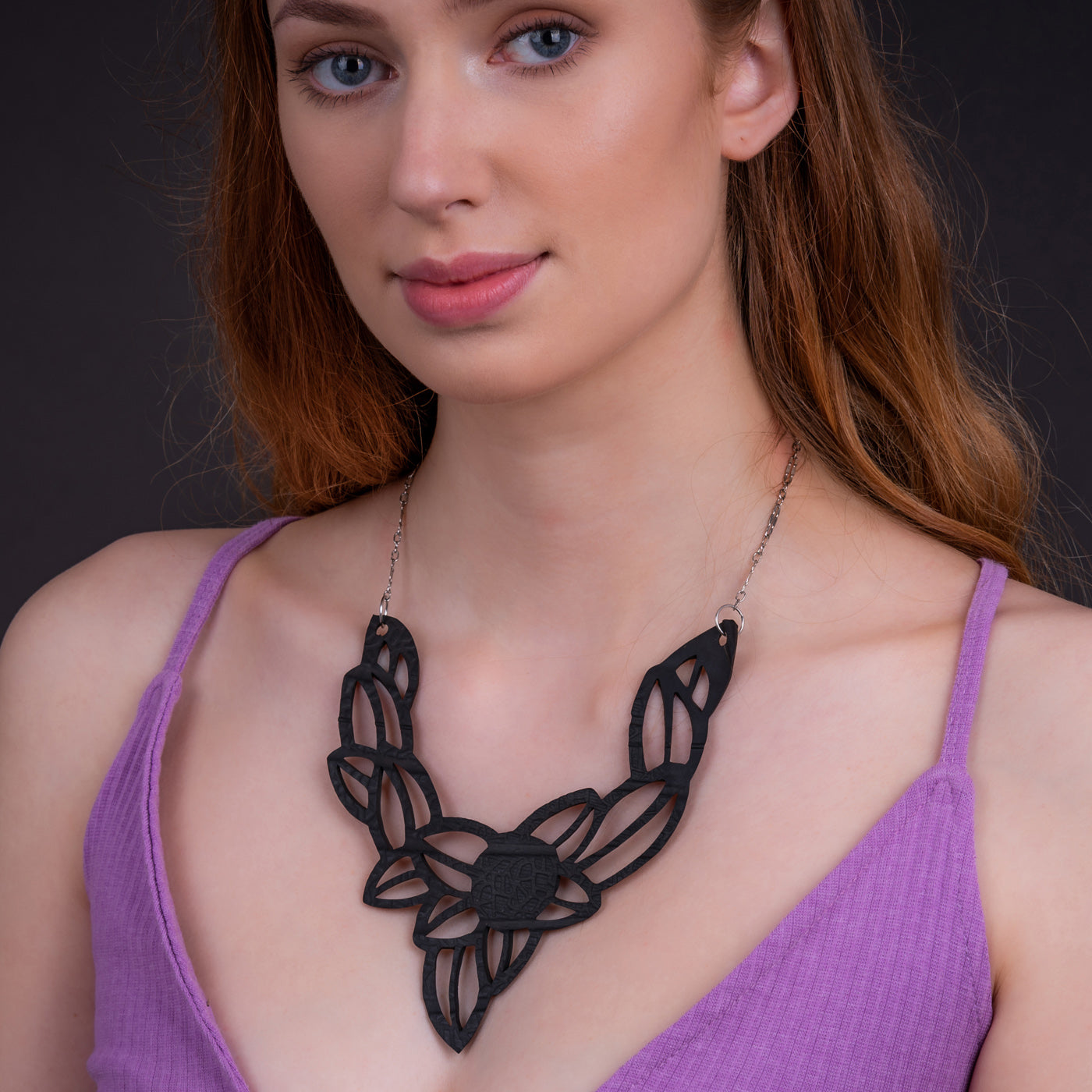 Paguro Upcycle vegan inner tube necklace worn by woman in purple top with intricate black design