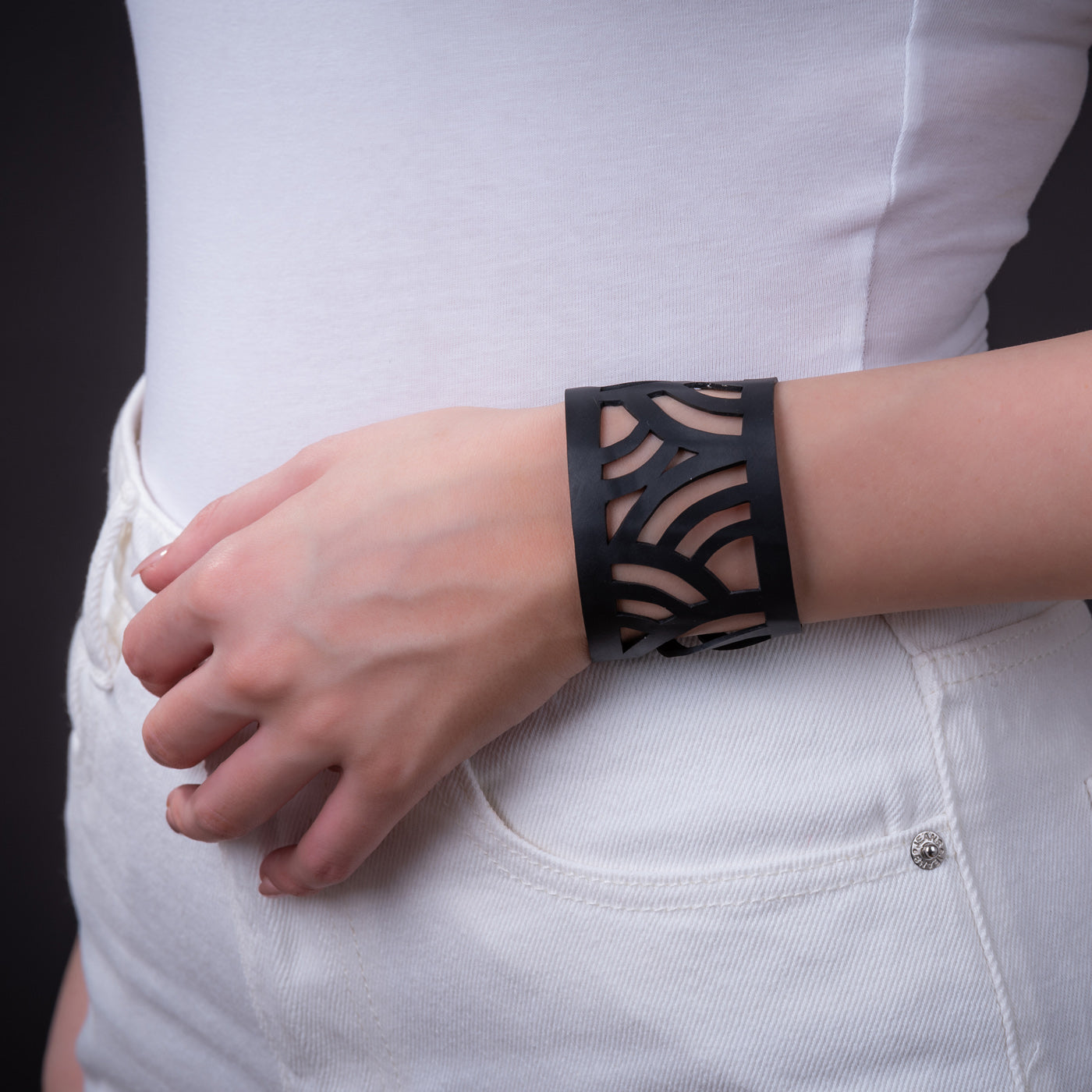 Paguro Upcycle black cuff with geometric cutouts on model wrist wearing white top recycled rubber bracelet