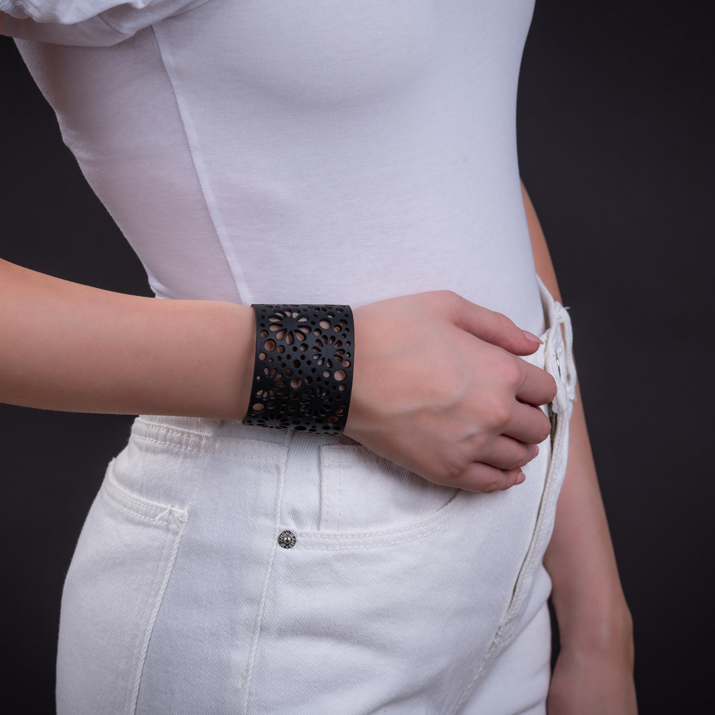 Paguro Upcycle black laser cut recycled rubber bracelet cuff on model wearing white top and jeans