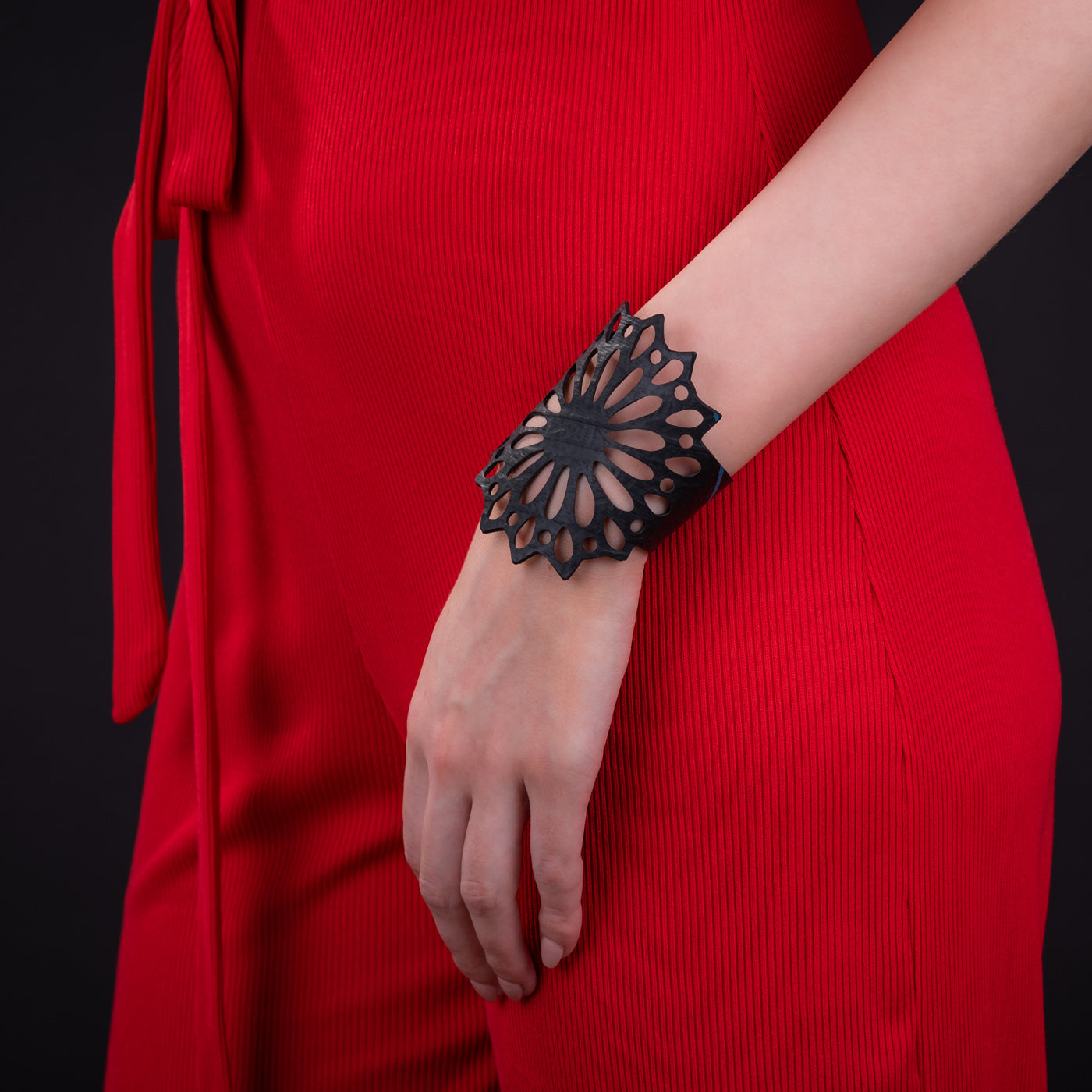 Paguro Upcycle black floral cutout recycled rubber bracelet worn on wrist with red dress for modern upcycled style