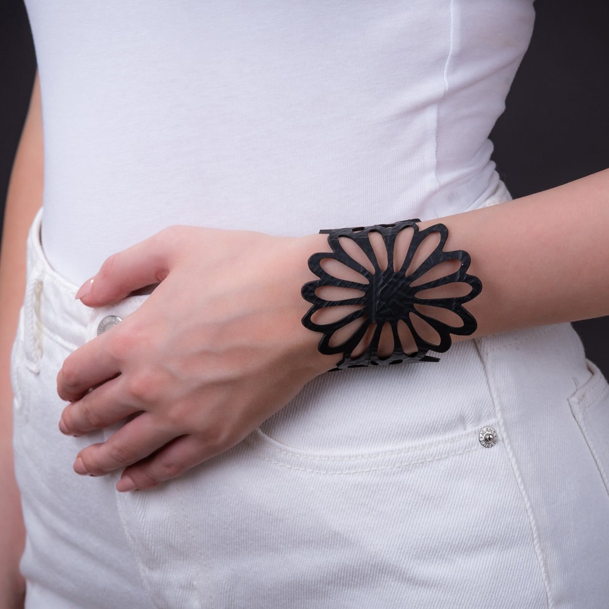 Paguro Upcycle black recycled rubber bracelet with floral design worn on wrist with white outfit