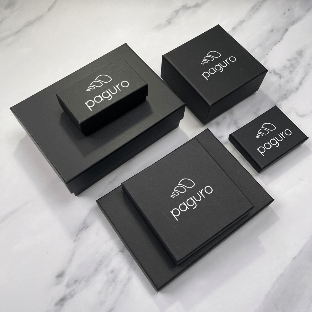 Paguro Upcycle black packaging boxes for recycled rubber bracelet on marble surface