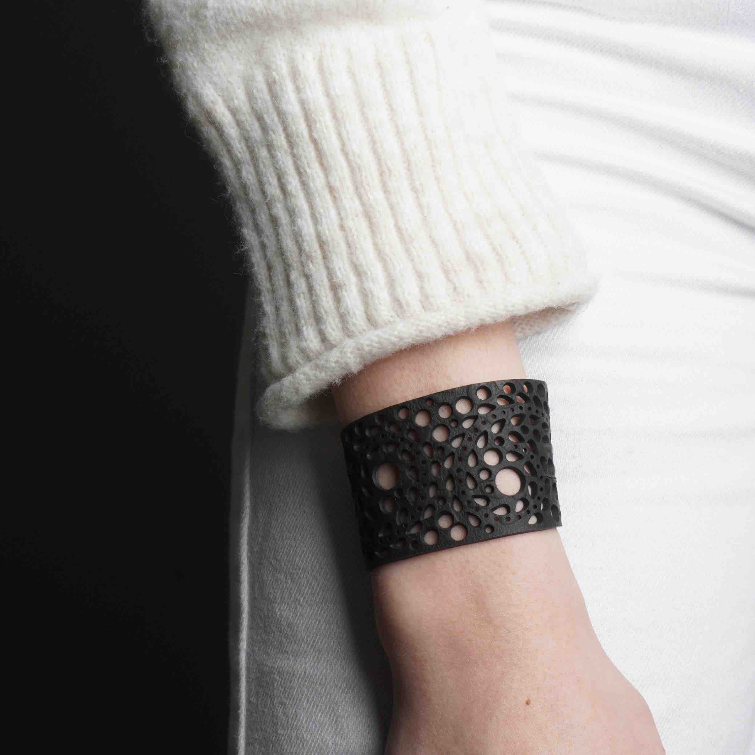 Paguro Upcycle recycled rubber bracelet with circular cutout design worn on wrist with white sweater