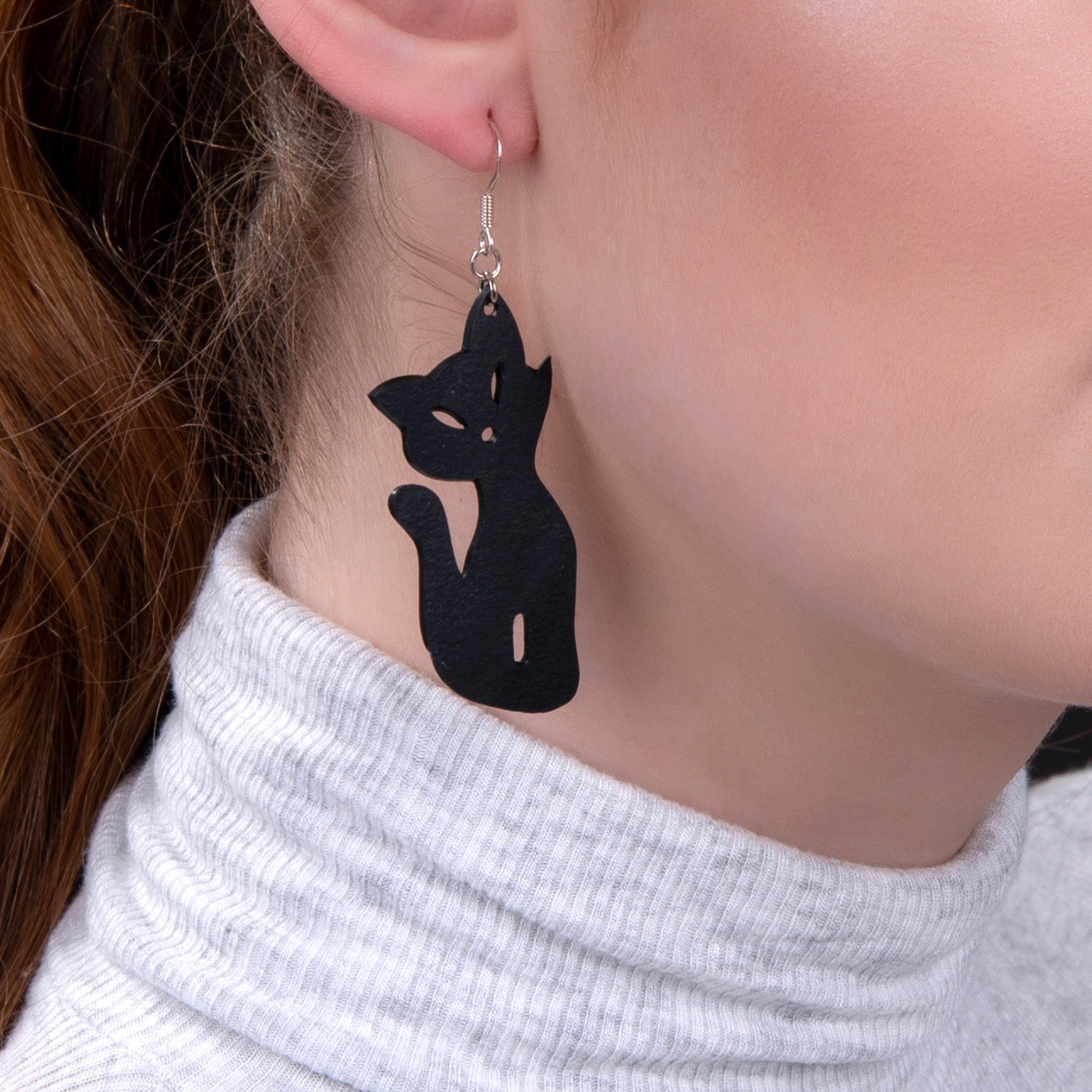 Paguro Upcycle recycled rubber cat earrings worn on ear showing black cat silhouette design