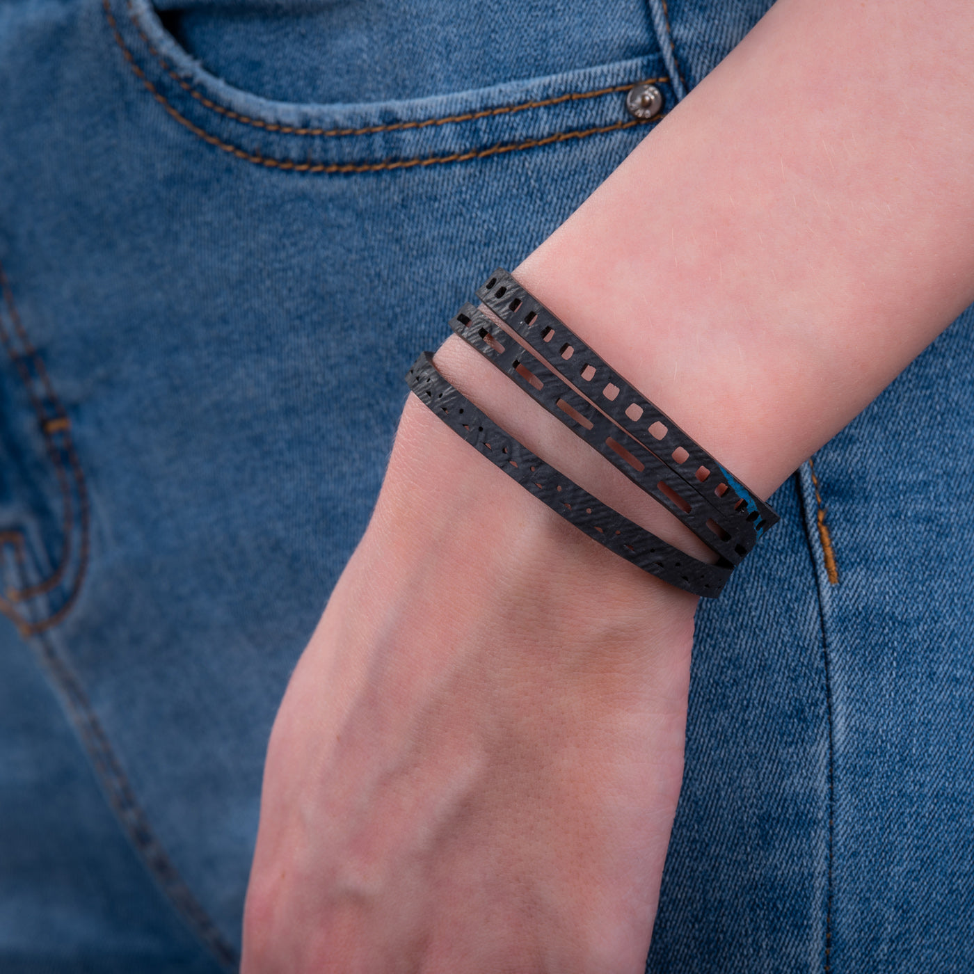 Paguro Upcycle black upcycled inner tube bracelet wrapped around wrist with denim jeans background